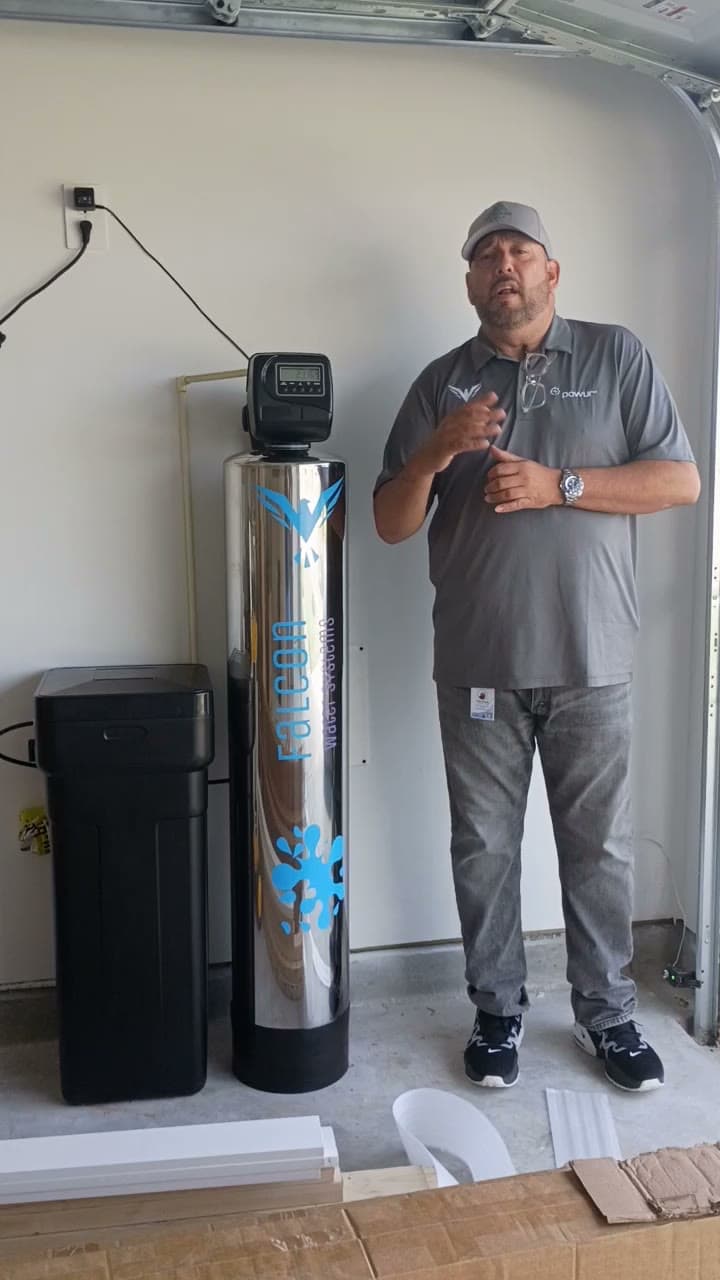 Noel Falcon next to a finished stainless water softener install in a Houston garage